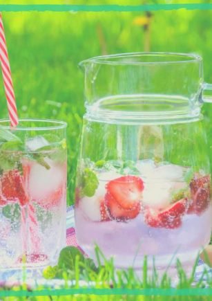 Ice-cold summer cool herbal drinks, with strawberries, put on a grass green background, reflecting an article on best summer cooling herbs for refreshment.